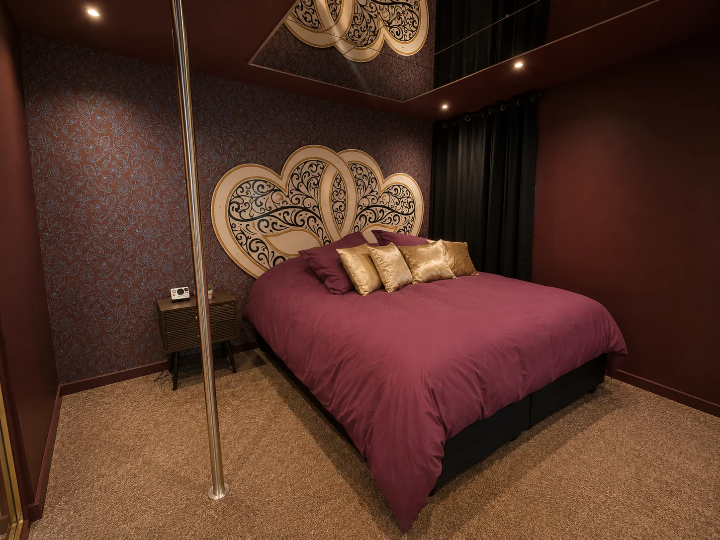 Chambre avec lit, miroirs et pole dance dans la Love Room &agrave; Wissembourg